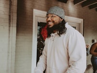 a man with long hair and a hat is smiling